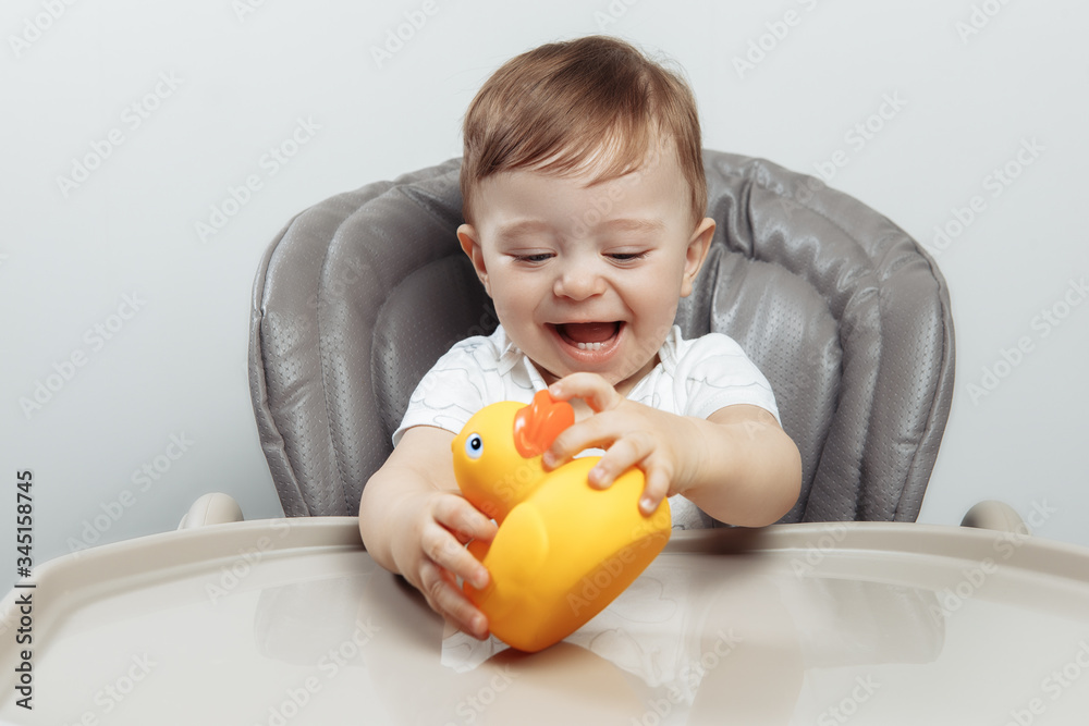 Funny adorable baby boy play with duck toy in high chair. Funny adorable baby boy play with duck toy in high chair.