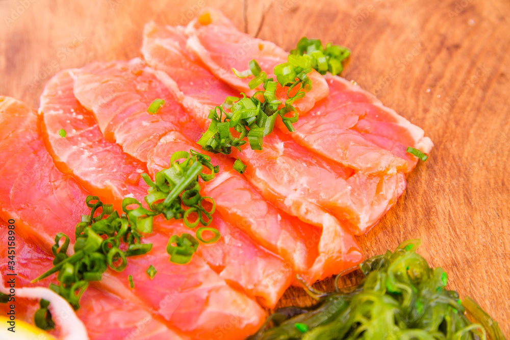 Fish platter on a wooden board. Lightly salted salmon, chuka salad and green onion decor Fish platter on a wooden board. Lightly salted salmon, chuka salad and green onion decor
