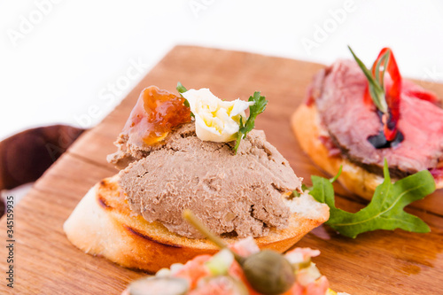 Assorted bruschett on a wooden board on a white background