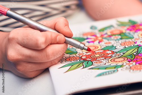 Detail of a girl coloring a flower mandala with a red marker