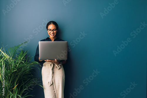 Beautiful businesswoman standing at home and holding laptop computer oh hands