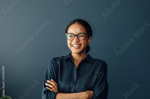 Happy businesswoman with crossed arms standing at home and looking away