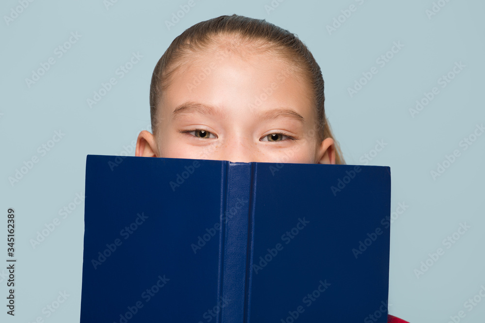 Schoolgirl covers her face with a book. Eyes portrait
Schoolgirl covers her face with a book. Eyes portrait