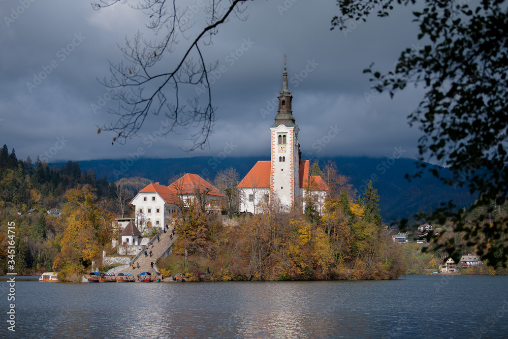 Santa Maria Church catholic church situated on an island on Bled lake with Alps mountains on the background. Autumn nature landscape.