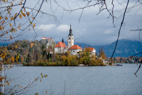 Panoramic view of Santa Maria Church on the alpine Bled Lake (Blejsko jezero) in autumn , Slovenia. Scenic view of the lake, island with church, Bled castle, mountains and blue sky with clouds photo