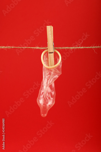 One condom hanging on washing line over red
