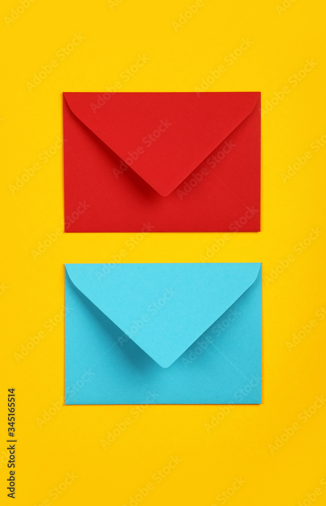 Two closed blue and red paper envelopes on yellow
