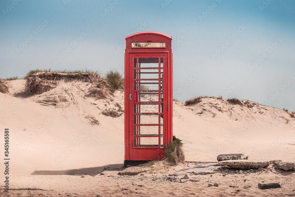 A vintage red telephone box in the sand dunes of a deserted beach near Sandbanks, Studland, Dorset, England, UK
