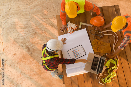 Top view of architectural engineer working on his blueprints with documents on construction site.focus on engineer.Team of young man and woman engineer and architects working.