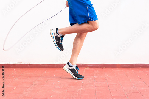 Legs of a man working out with a skipping rope on the terrace of his house