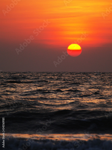 Fototapeta Naklejka Na Ścianę i Meble -  golden sunrise sunset twilight hour. sun rays reflecting on sea water and shore vertical orientation