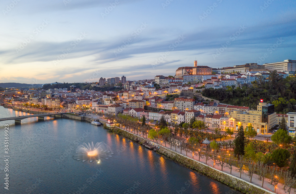 Coimbra drone aerial city view at sunset with colorful fountain in Mondego river and beautiful historic buildings, in Portugal