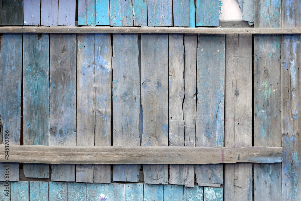 Texture of blue paint on a wooden surface of the fence. Grunge retro background. Old wooden blue slats with faded paint background. Vertical narrow boards close up.
