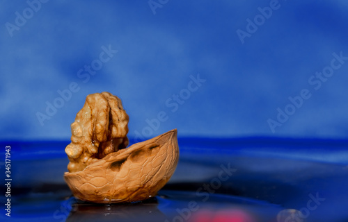 Composition of walnuts on a blue background. The boat is floating on the water. Macro, abstraction. Copy space.