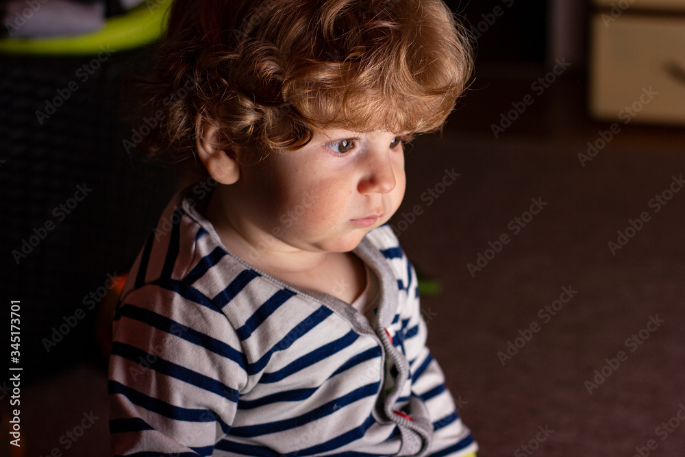 A child in a zebra costume. Little boy is playing in a dark room. Baby in pajamas.