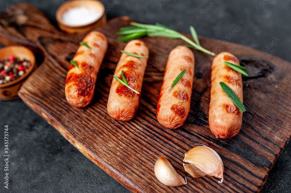 classic grilled sausages with spices on a cutting board on a stone background