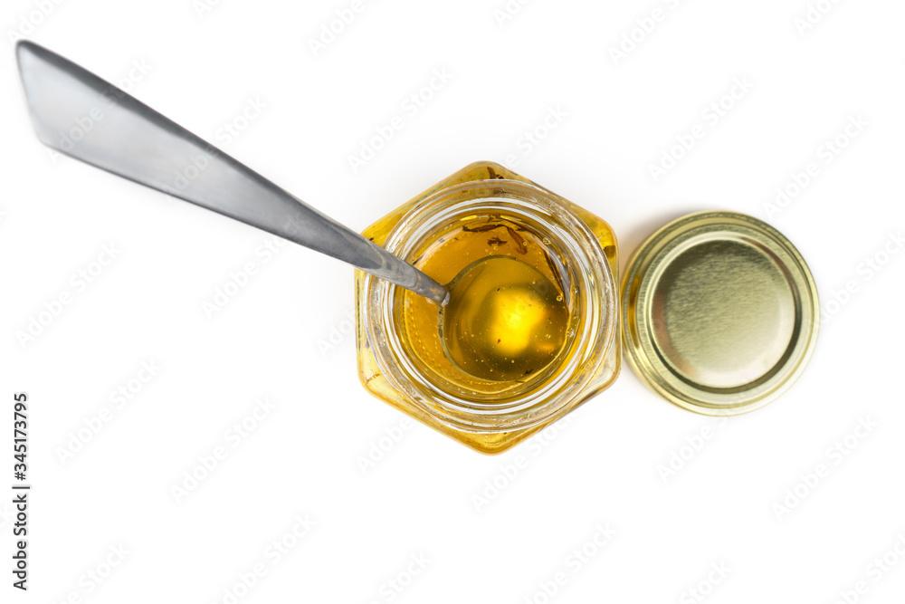 Tea spoon in a hexagonal honey jar isolated on white. Top view. Tea spoon in a hexagonal honey jar isolated on white. Top view.
