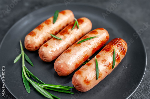 classic grilled sausages with spices in a plate on a stone background