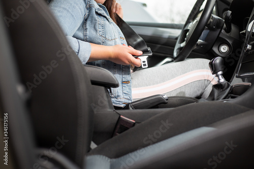 Driver woman fastening seat belt in the car, against car crash, safety concept, safe transport