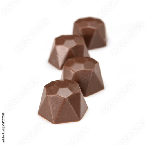 Chocolate pralines. Four dark chocolate bonbons with hazelnut fillings, macro close-up isolated on white background.