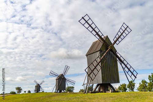 Three old windmills on a green sunny field