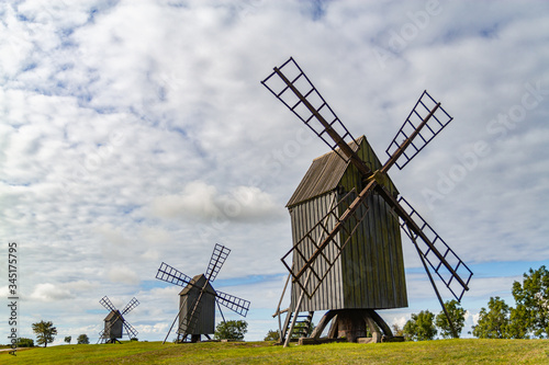 Three old windmills on a green sunny field