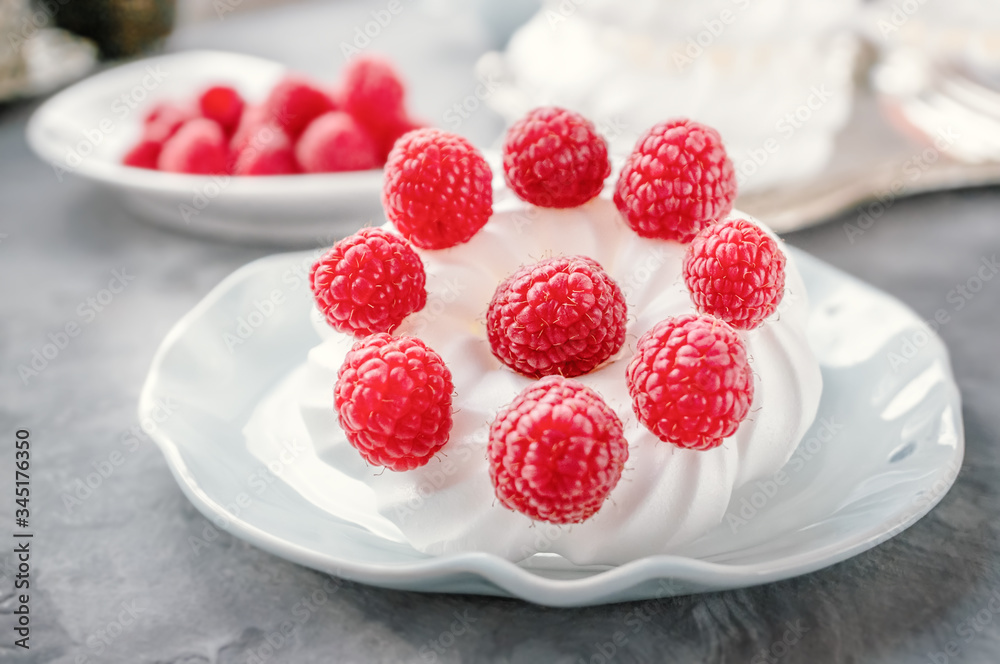 Delicious mini Pavlova meringue cake decorated with fresh raspberries, with a beautiful Cup lying on a platter Delicious mini Pavlova meringue cake decorated with fresh raspberries, with a beautiful Cup lying on a platter