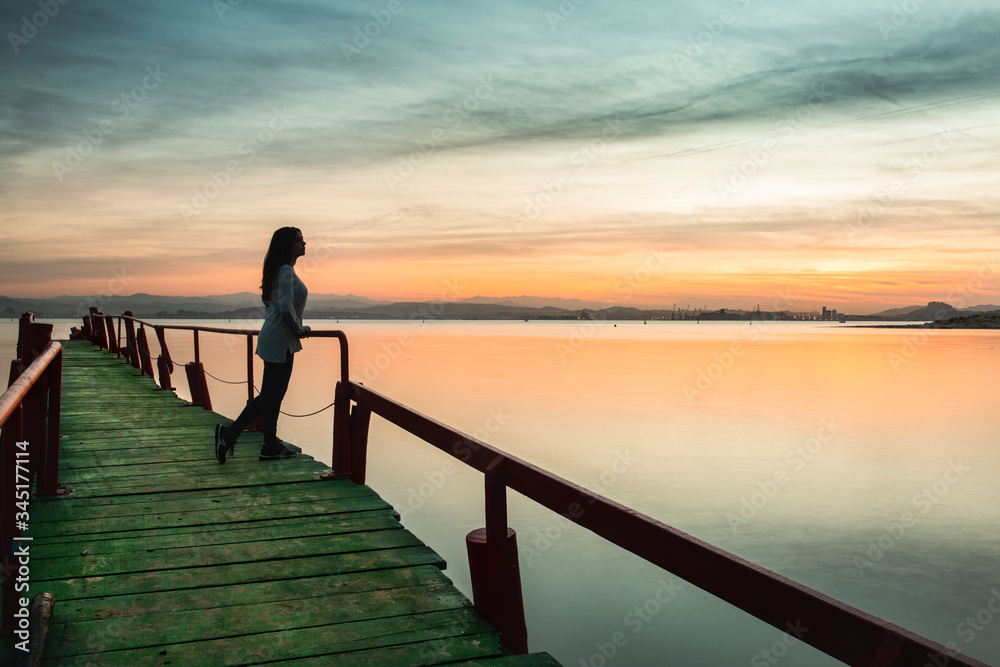 Fototapeta premium woman walking on pier at sunset