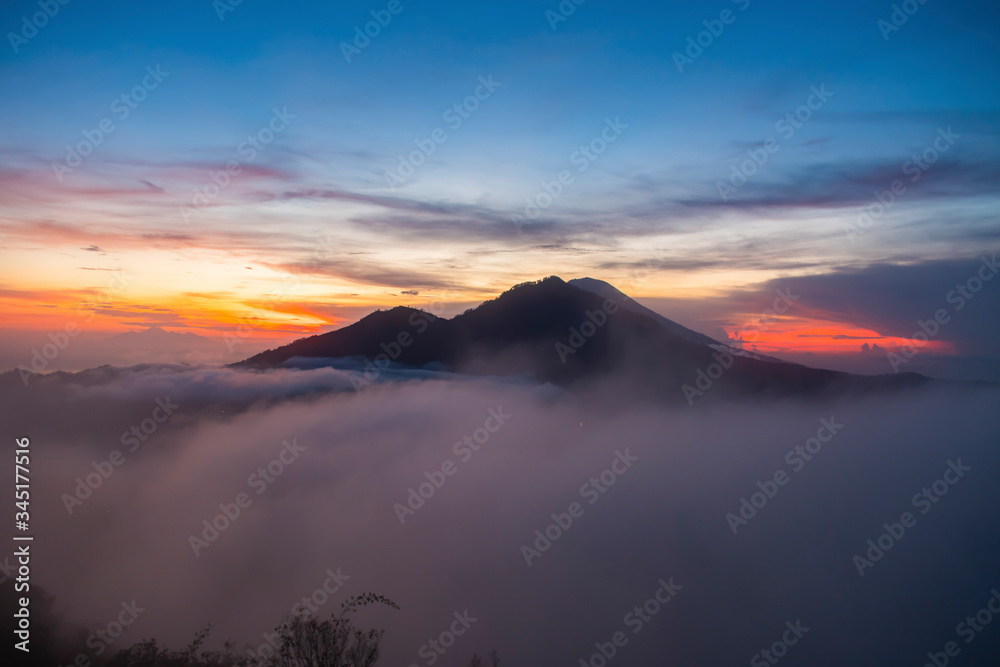 A magnificent view of kintamani volcano from the top of the Mount Batur during the sunrise with fog