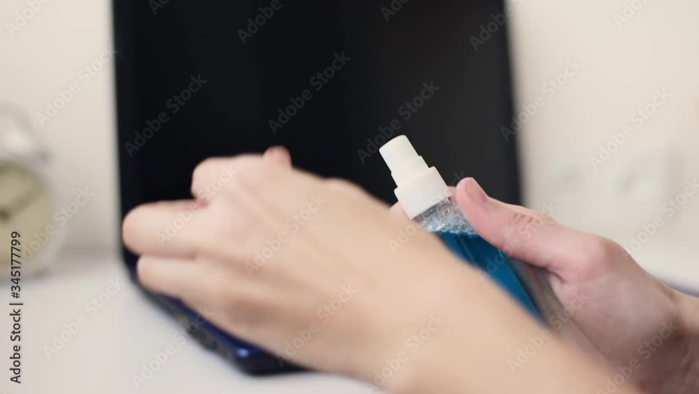 Disinfection gadget to protect from coronavirus covid-19 outbreak. Cleaning hand with antibacterial antiseptic sanitizer spray before working at laptop Disinfection gadget to protect from coronavirus covid-19 outbreak. Cleaning hand with antibacterial antiseptic sanitizer spray before working at laptop