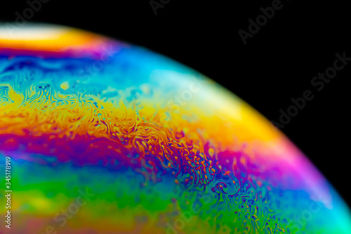 Psychedelic abstract planet from soap bubble, Light refraction on a soap bubble, Macro Close Up in soap bubble. Rainbow colors on a black background. Model of Space or planets universe cosmic galaxy.