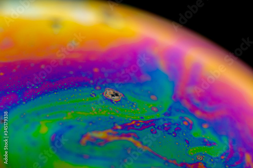 Psychedelic abstract planet from soap bubble, Light refraction on a soap bubble, Macro Close Up in soap bubble. Rainbow colors on a black background. Model of Space or planets universe cosmic galaxy.