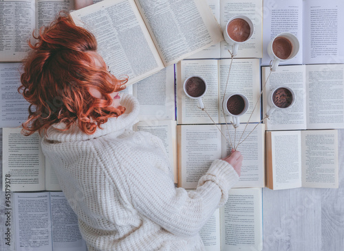 Girl sleeping near books with and cups of coffee photo