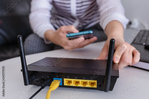 Canvas Print closeup of a wifi router and a woman using smartphone on living room at home ofi