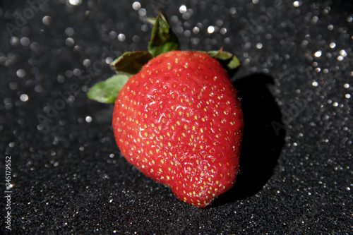 One strawberry on a black background. Berry on a black shiny background.