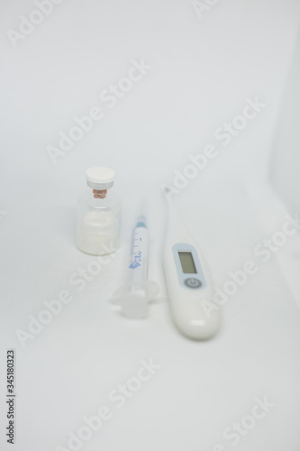 thermometer, syringe and ampoule with vaccine. medication for coronavirus. the coronavirus epidemic.Covid-19 Vaccine. Concept of vaccination, treatment and medicine infectious: thermometer, syringe 