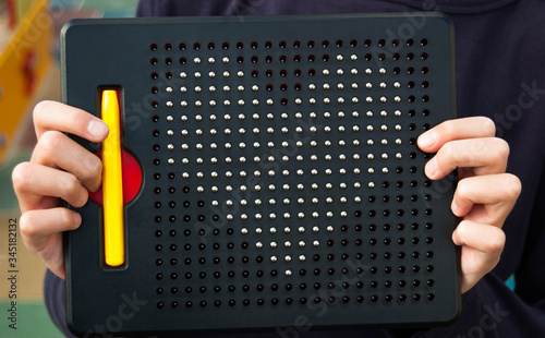 Close-up of a mosaic for children with the image of a heart in the hands of a child. Metal heart on a children's black magnetic puzzle. The concept of children's and teenage love. Children toy. 