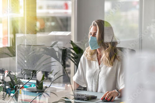 Executive woman working at her desk and wearing a protective mask against covid-19 photo