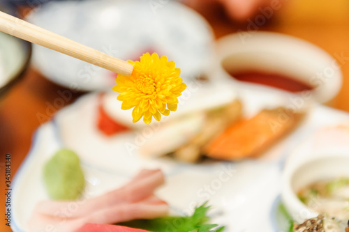 食用菊の刺身を箸でつまんで持ち上げる