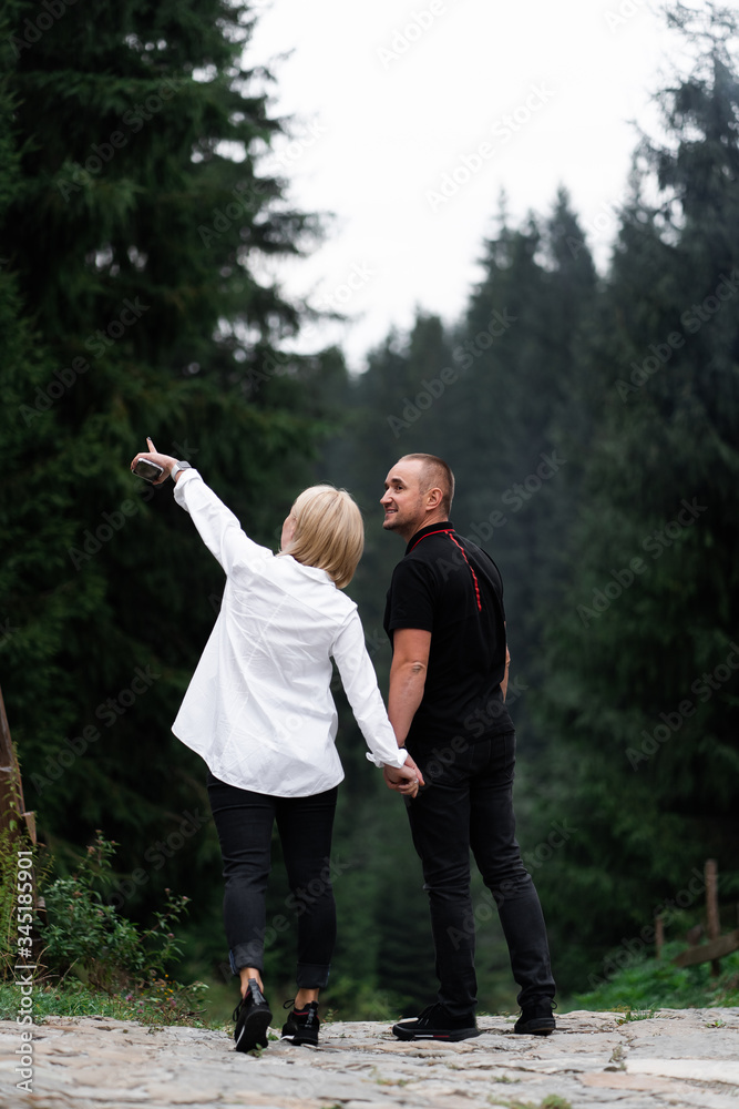 Obraz premium A man next to a woman, guy and a girl are standing close, touching each other, holding hand on forest background. Boy and girl, couple. Intimacy, honesty, trust. Bright future. Couple