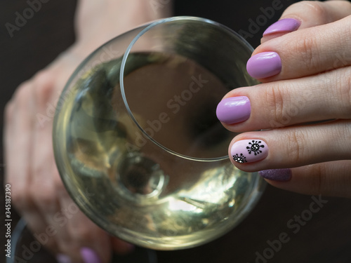 Hand and glass of wine. Creative manicure with painted coronavirus on the nails, soft focus, close up