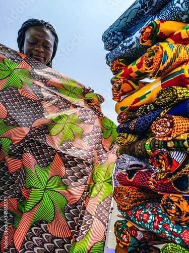 Konstfotografi Ghana woman looking at various fabrics in Accra market located in Ghana West Africa