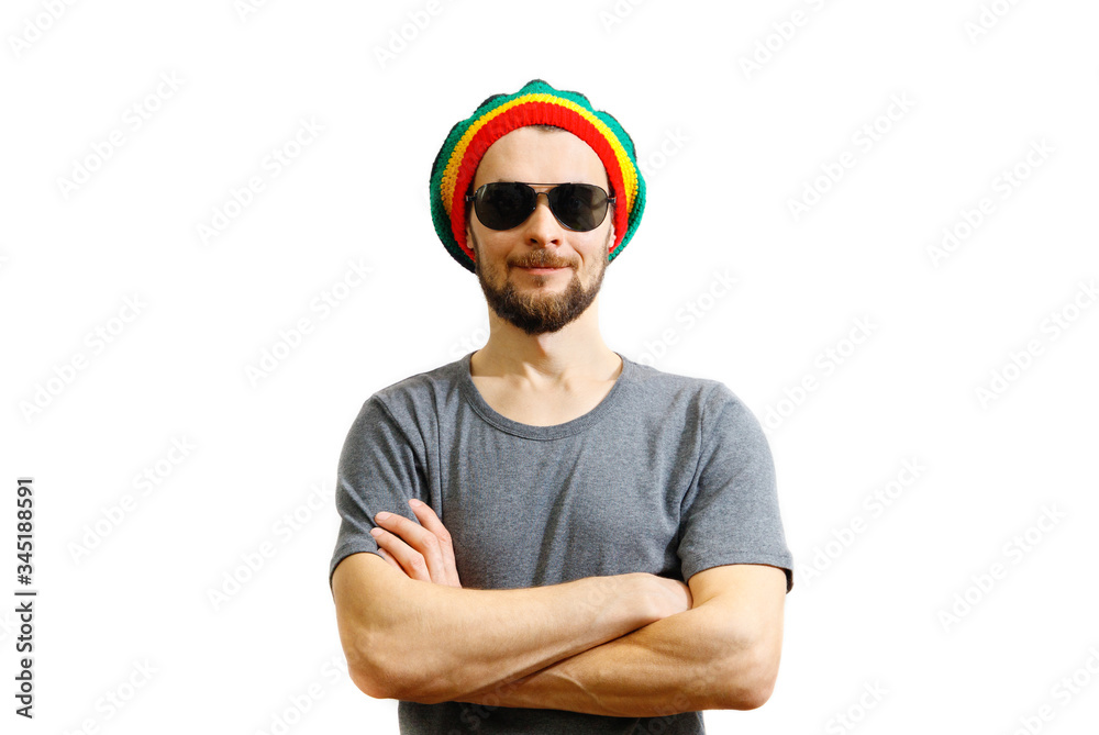 Young caucasian smiling man in rasta hat, sunglasses and grey t-shirt on white background laughing and having fun. Young caucasian smiling man in rasta hat, sunglasses and grey t-shirt on white background laughing and having fun.