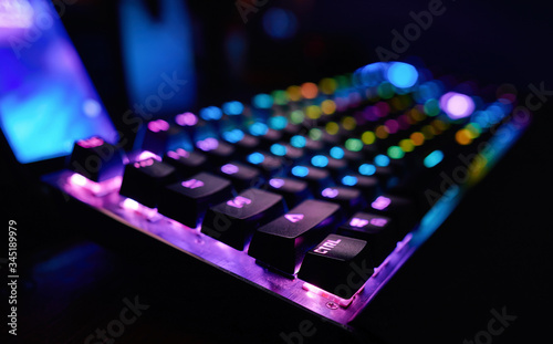 Premium Gaming RGB LED backlit keyboard. Mostly purple and blue. Side view.