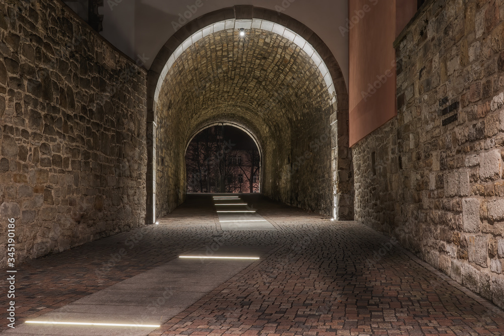 An old illuminated historic tunnel in the old town and old stones on the walls