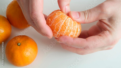 Hand Peeling a mandarin orange on white background. Close up.