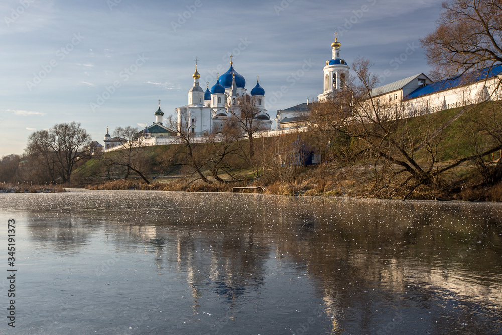 A beautiful white church stands on a lake is reflected in the ice