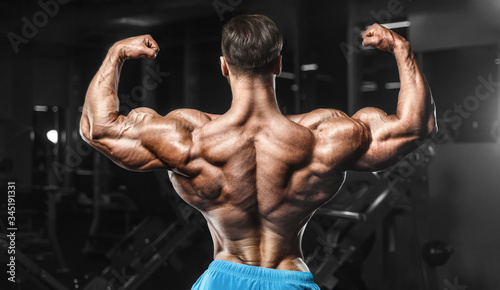 Bodybuilder strong man pumping up biceps muscles