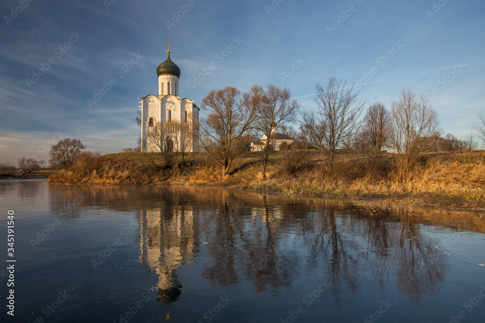 A beautiful temple on a background of bright golugobo sky stands on the shore of a lake is reflected in the ice at sunset A beautiful temple on a background of bright golugobo sky stands on the shore of a lake is reflected in the ice at sunset