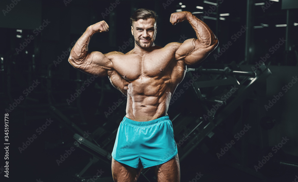 Obraz premium Bodybuilder strong man pumping up biceps muscles